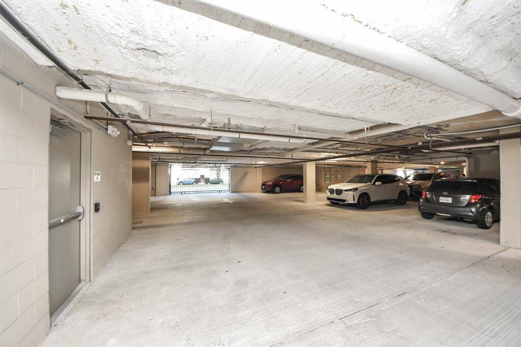 This photo shows a spacious, well-lit underground parking garage a secure entrance.