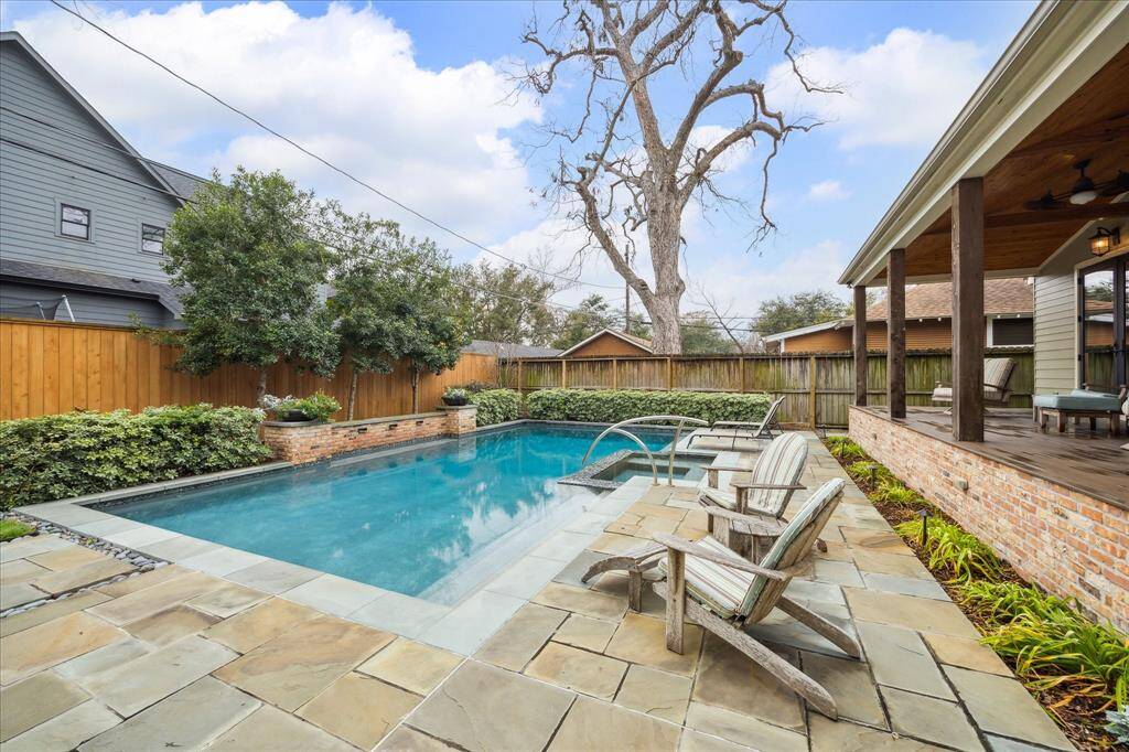 The beautifully designed large saltwater pool, complete with an attached hot tub and water feature, boasts spacious seating areas for lounging.