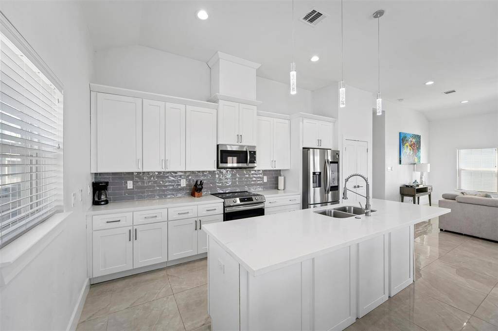This bright and modern kitchen is a chef’s dream, featuring sleek quartz countertops, stainless steel appliances, and ample cabinet space.