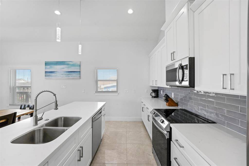 This beautifully designed kitchen features sleek quartz countertops, a spacious island, and high-end stainless steel appliances.