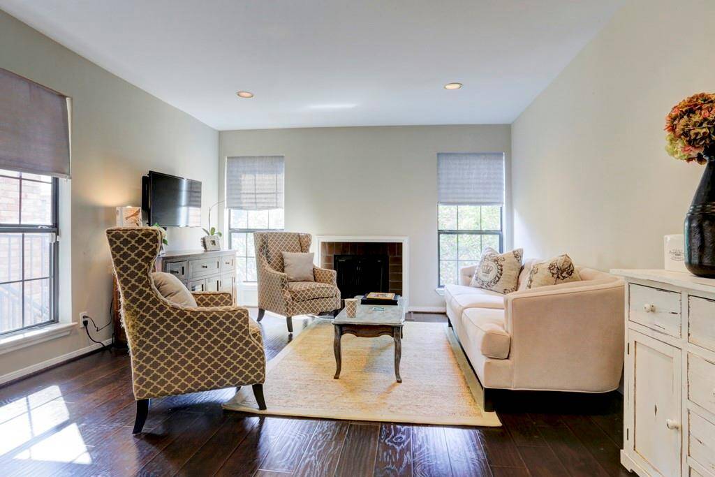 The Primary bedroom features a cozy atmosphere with high celings and views of the treetops. Natural light filters through the updated windows, highlighting the elegant updated dark wood floors. Perfect for a serene retreat.