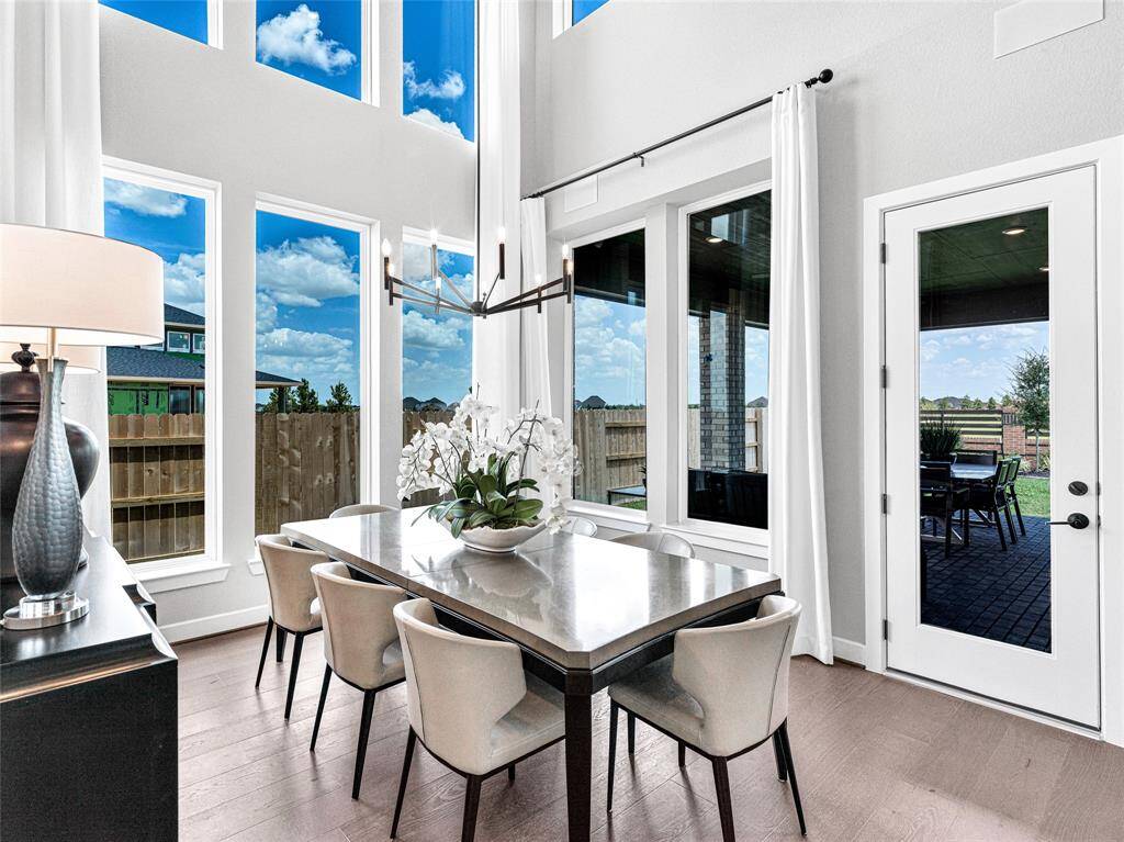 Features a modern chandelier, a sleek dining table, and views of the backyard patio.