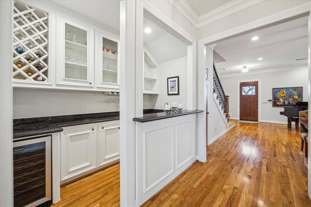 This exquisite wet bar is equipped with a wine refrigerator, wine storage, elegant glass-front cabinets for display, and sleek granite countertops.