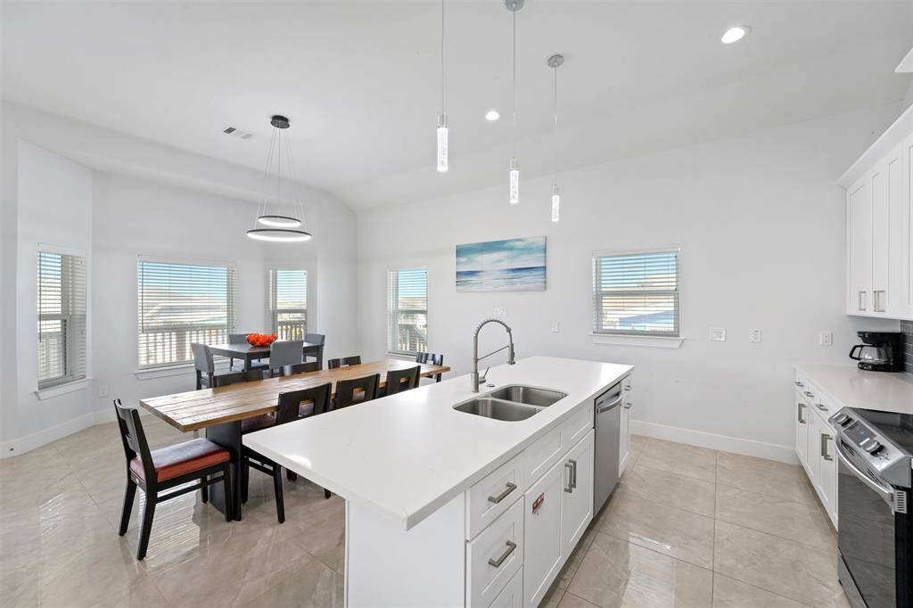 This open and airy kitchen and dining space is designed for effortless entertaining. With a spacious island, modern finishes, and abundant natural light, it's the perfect place to gather with family and friends after a day at the beach.