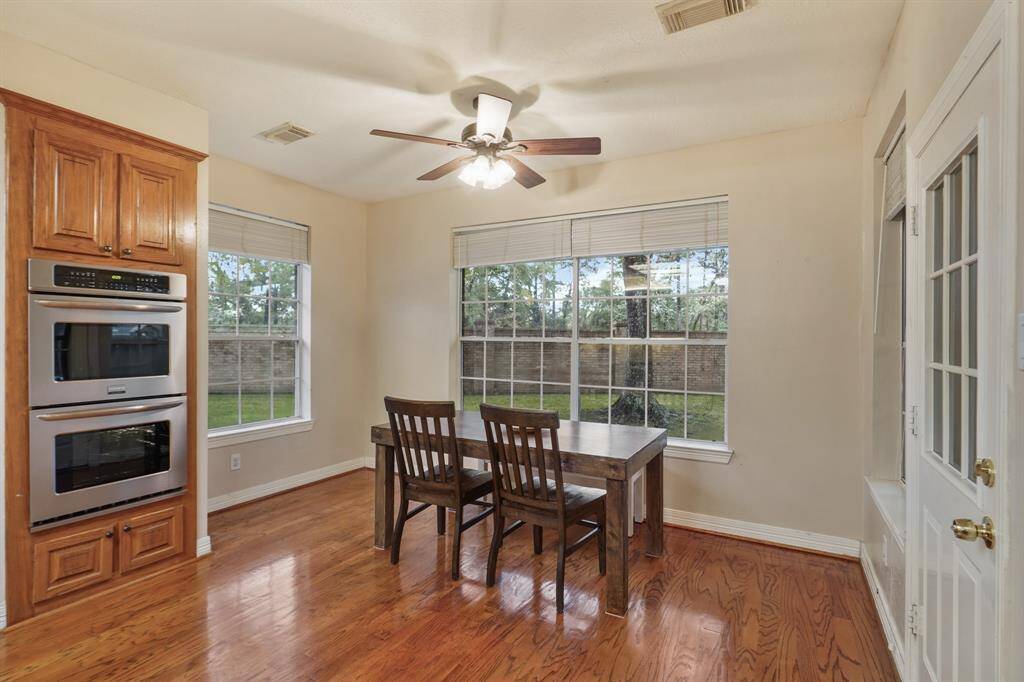Charming breakfast area, complete with wood floors, a ceiling fan, and beautiful views of the backyard are provided by several windows.