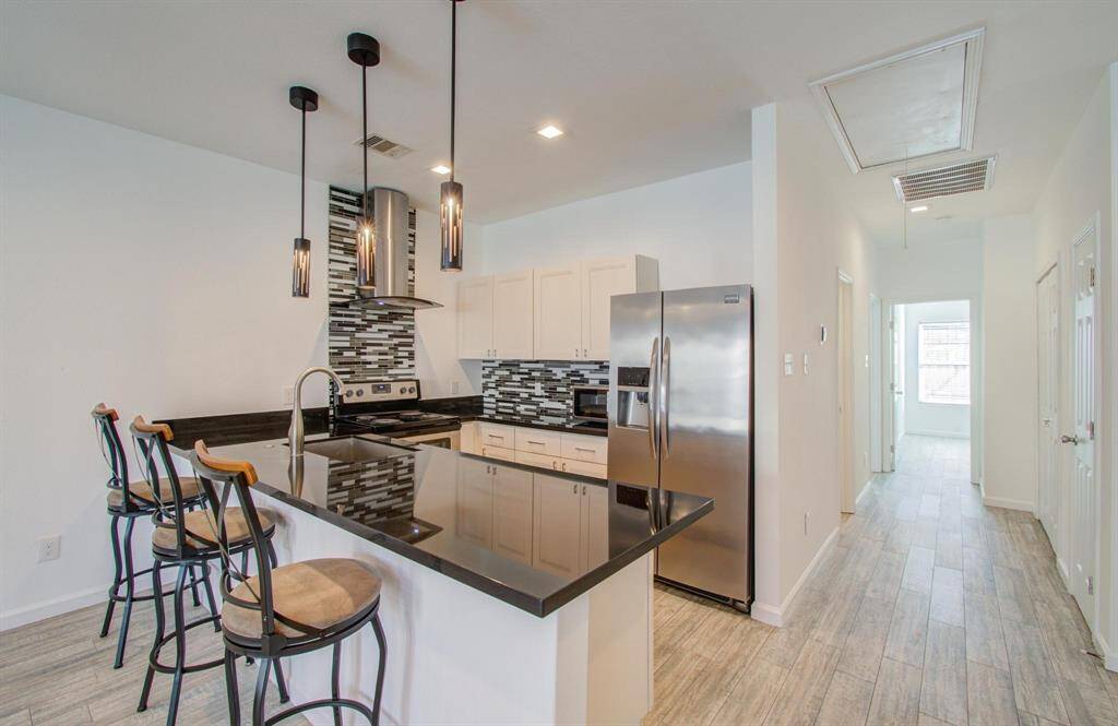 View of modern kitchen opening into a bright hallway leading to bedrooms, bathroom and laundry.