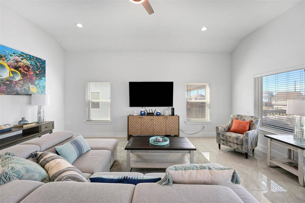 This beautifully designed living room offers the perfect blend of comfort and style. Natural light pours in through large windows, highlighting the open floor plan and coastal-inspired décor.