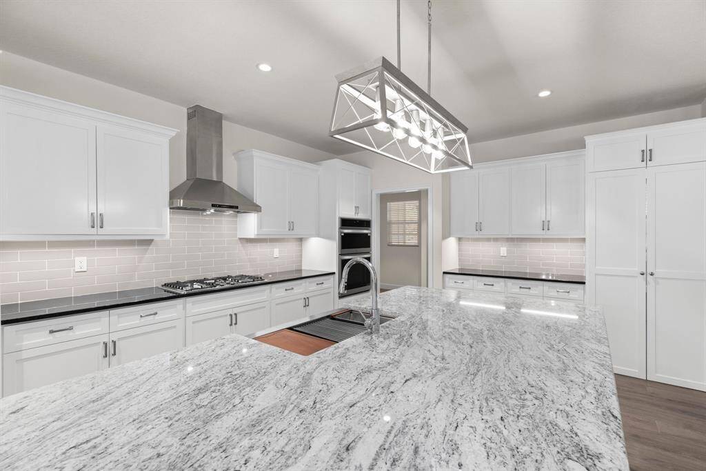 Gorgeous kitchen! Granite counter tops, custom cabinets, stainless steel farm house sink with accessories! Large hidden pantry right through those double cabinet doors.