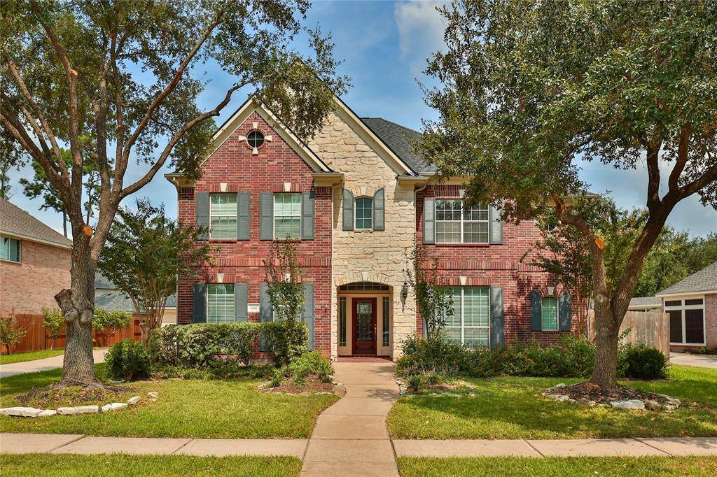 This home has great curb appeal with lush landscaping, shuttered windows, and a brick and stone facade.