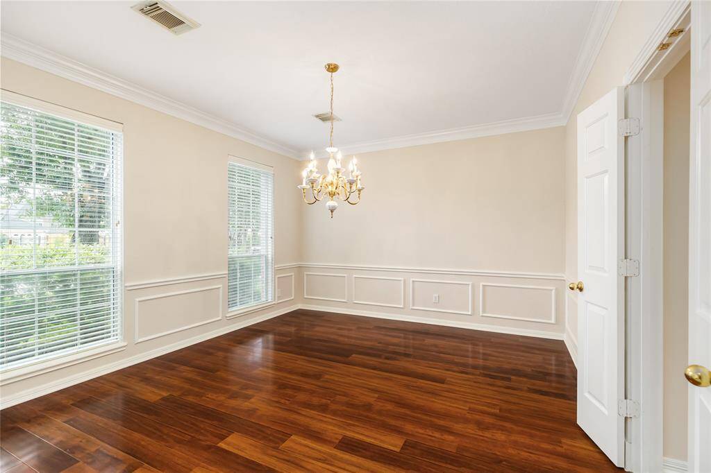 The Formal Dining Room features wood floors, extensive molding, and faces the front yard.