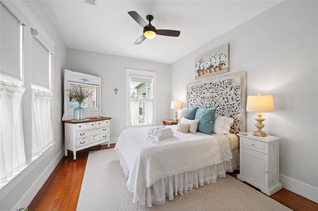 Large secondary bedroom with custom blackout shades and original hardwood flooring.