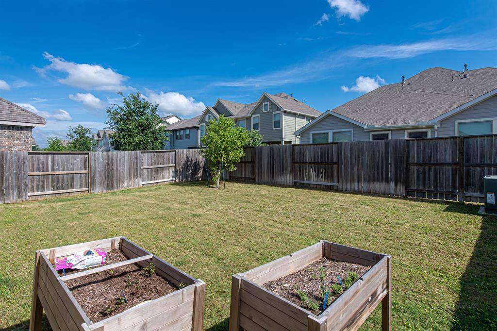 Spacious backyard with a well-maintained lawn, wooden fencing for privacy, and two raised garden beds, perfect for gardening enthusiasts. Ideal for outdoor activities and relaxation.