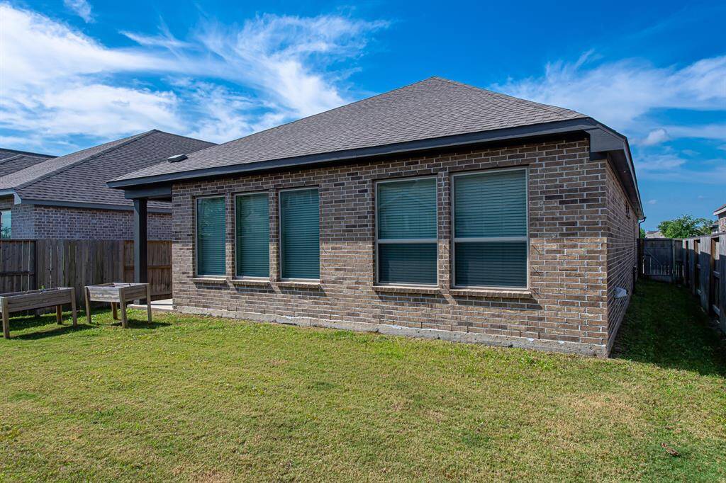This photo shows the backyard of a brick home with a grassy yard, a wooden fence, and multiple windows. It's ideal for privacy and outdoor enjoyment.