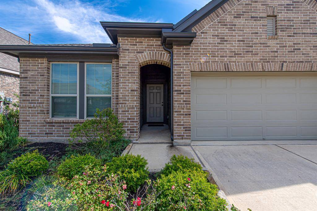 This photo showcases a modern brick exterior home with a neatly landscaped front yard. It features a two-car garage and a welcoming entryway with a covered porch.