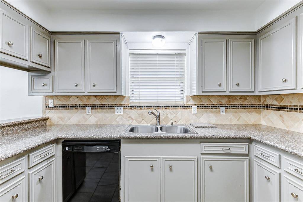 The double-basin, over-mount sink is perfectly positioned beneath a large window that frames a peaceful view of the side yard and towering trees. To the left, you'll find the convenient dishwasher, adding functionality to this beautiful space.