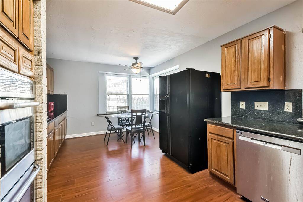 This kitchen features hardwood floors, ample natural light, and a cozy dining area. It includes stainless steel appliances, wooden cabinetry, and a modern ceiling fan, offering both style and functionality.