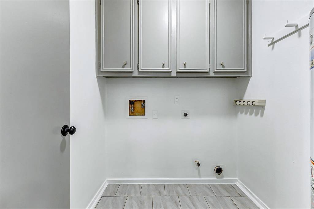 The laundry room features built-in cabinetry that offers plenty of storage for all your laundry essentials, keeping everything organized and out of sight. This practical space helps streamline your household chores, making laundry day more efficient while keeping your home clutter-free.