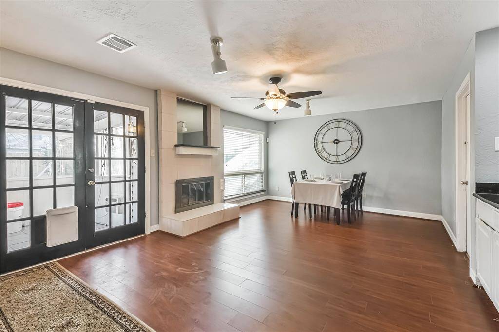 This inviting dining area features hardwood floors, a modern fireplace.  It opens to a bright sunroom through elegant French doors, and a ceiling fan adds comfort. Perfect for hosting dinners or cozy family gatherings.