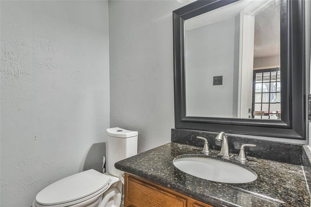 Cozy bathroom with a modern black granite countertop, undermount sink, and sleek faucet. The large mirror adds depth, and the neutral wall color provides a calm atmosphere. A window offers natural light, enhancing the space.