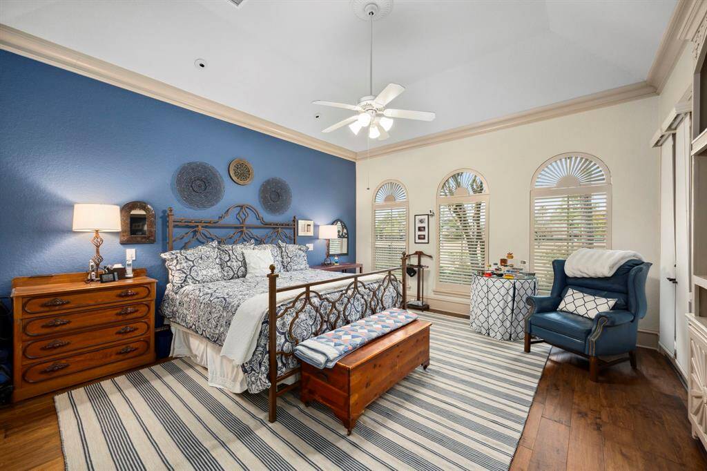 The spacious master bedroom features views of the golf course through custom wood shutters, back patio access, high ceilings and built ins.
