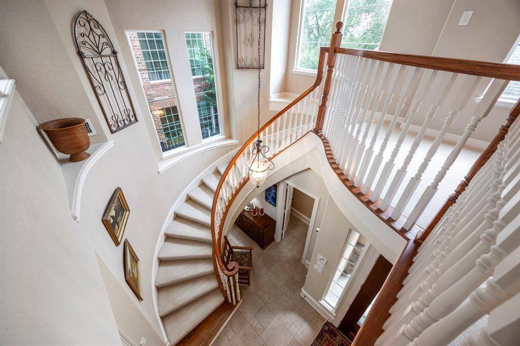 The gorgeous sweeping staircase(with half bath below) leads to the upstairs landing overlooking the courtyard.