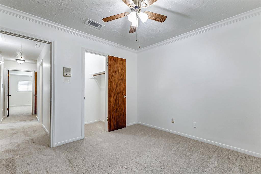 This view of bedroom four highlights the spacious walk-in closet and offers a glimpse of the home's layout, showcasing the well-appointed bedrooms and bathrooms nearby.