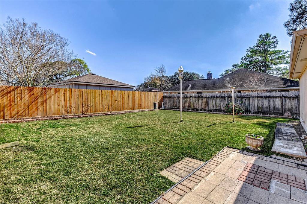 The lush green lawn extends toward a sturdy wooden fence, with one side recently replaced for added durability. Offering exceptional privacy, this backyard ensures a peaceful retreat where no neighbors can peek in, allowing you to fully enjoy your outdoor space in seclusion.