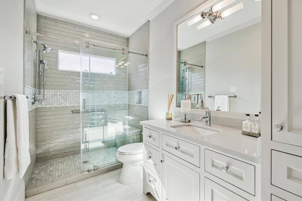 The ensuite bath is as lovely as the primary bath. Design features include Macaubus Wave quartz countertops, and a marble walk-in shower.