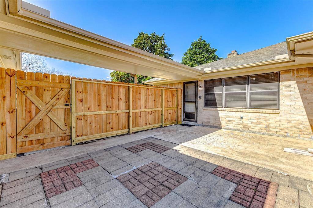 A closer look at the patio reveals a stunning blend of light concrete and red brick pavers, arranged in a geometric pattern for added charm. A recently replaced wooden fence with a gate encloses the space, ensuring privacy and security. Overhead, a catwalk seamlessly connects the back door of the home to your oversized garage, adding both convenience and architectural interest.