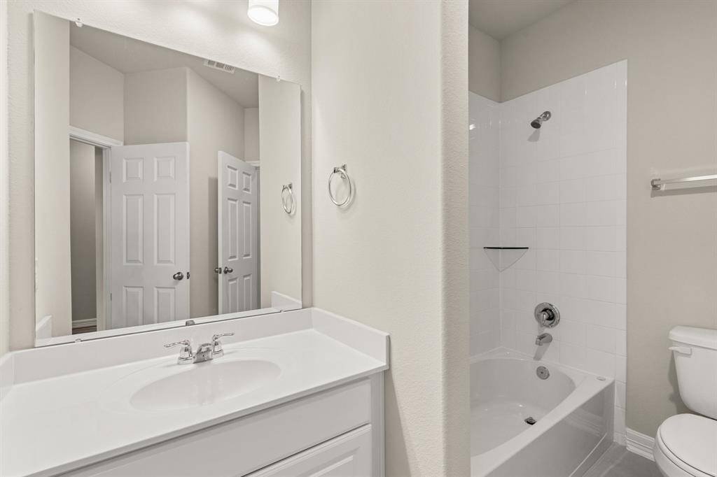 The secondary bath features tile flooring, white cabinetry and light countertops and a shower/tub combo. Perfect for accommodating any visiting family and friends.