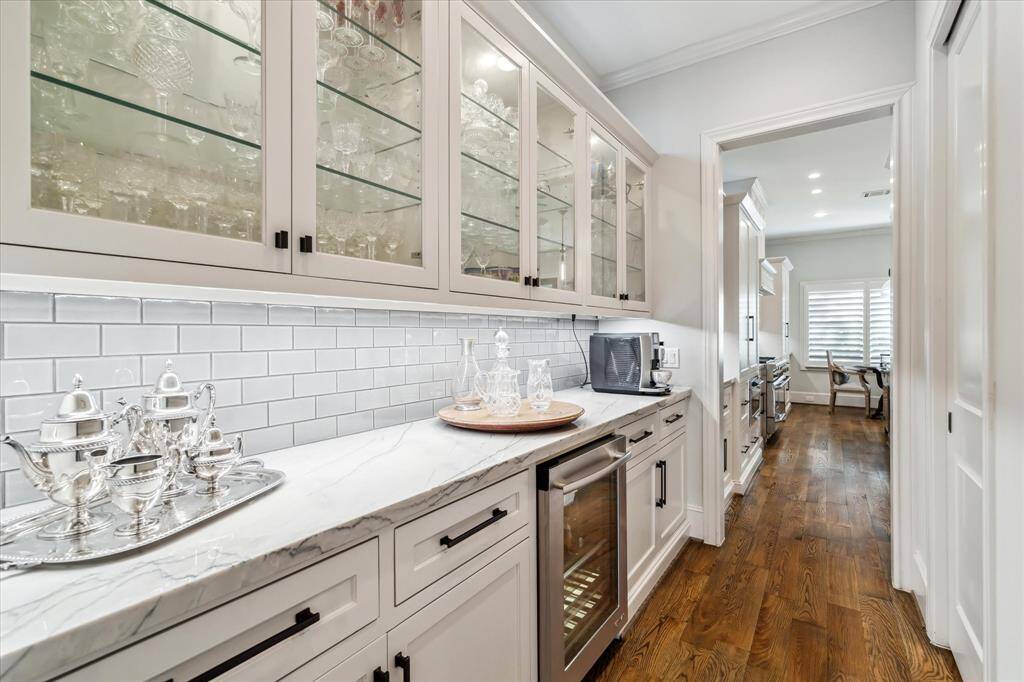 The owners designed this beautiful Butler's Pantry located between the Formal Dining and Kitchen. It is wonderful, oversized space! Giotto quartzite counters, beverage chiller, and glass front upper cabinets are a few of the special details. A sizable walk-in pantry is across from the butlers pantry.