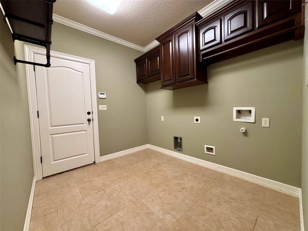 Utility room has custom built solid wood cabinets to match the kitchen, additional area for stand up freezer or additional refrigerator and plenty of room for additional utility room needs.