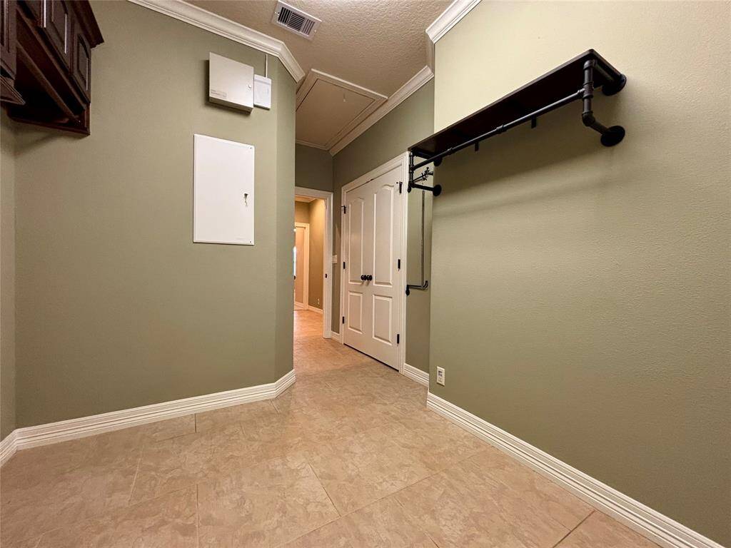 Utility room has custom shelving for holding items and hanging clothes as well as large closet space and access to alarm panel features.