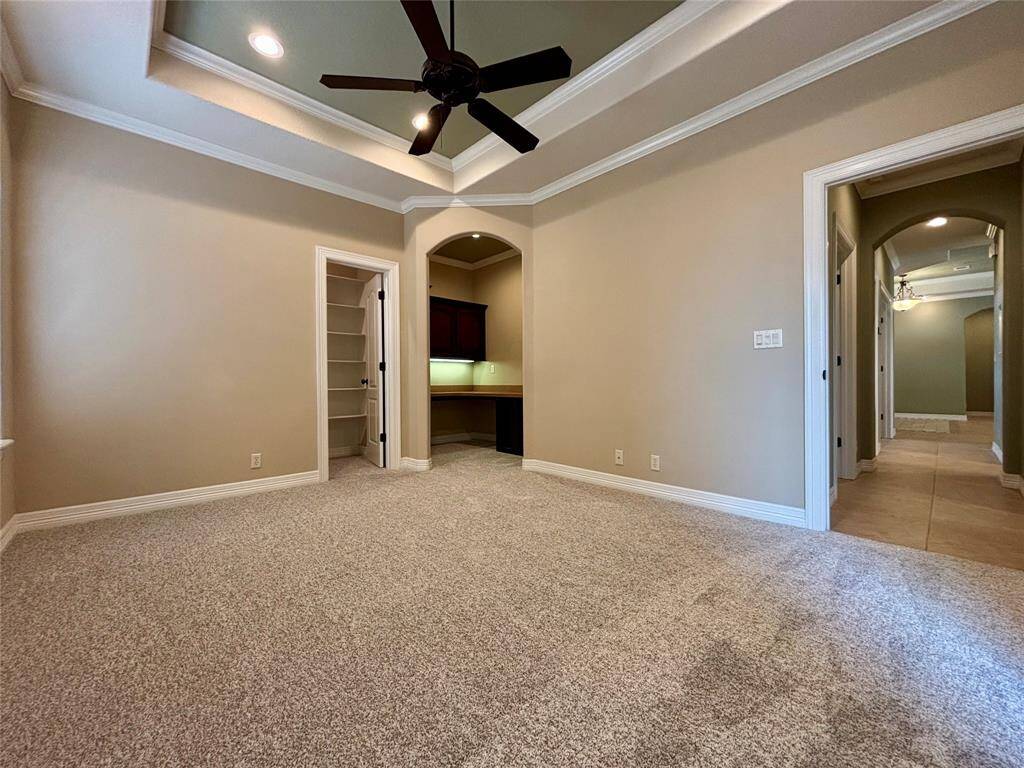 2nd bedroom located next to utility room offers tray ceiling, crown molding, very spacious closet space and custom built-in office space with desk, built-in cabinets and custom lighting.