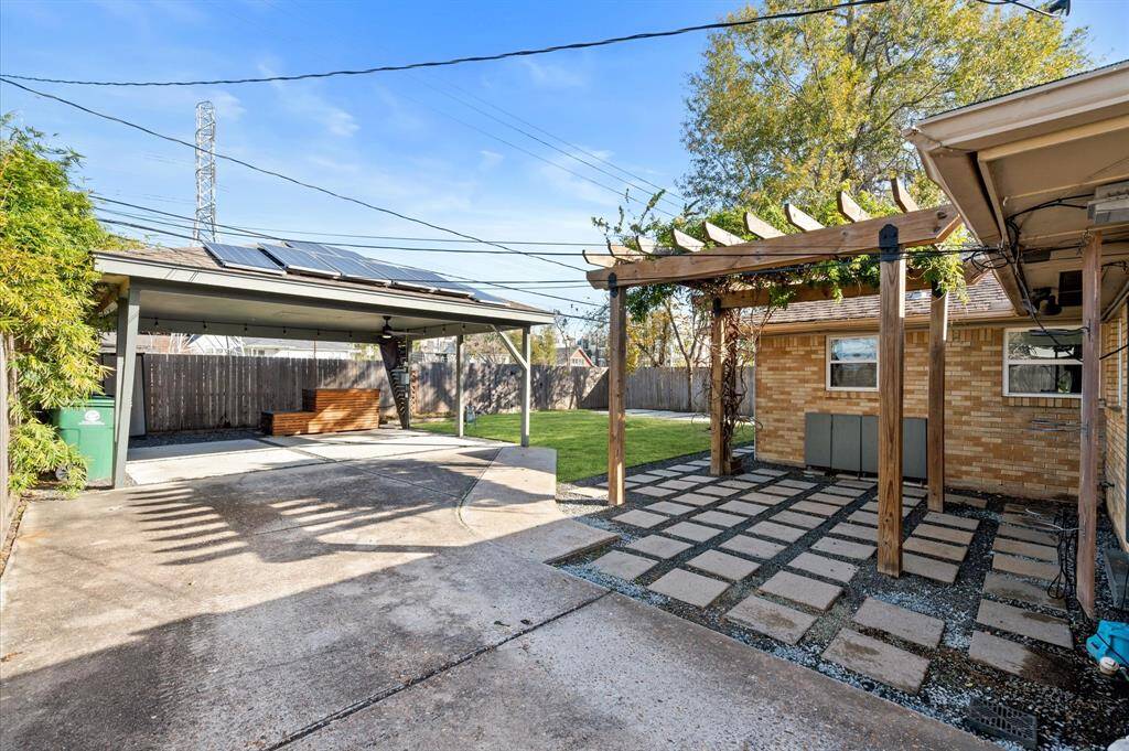 A large carport provides ample space for two cars, secured by a driveway gate. Carport also features a 220v outlet for EV charging, along with a ceiling fan and TV setup, perfect for entertaining large outdoor gatherings.