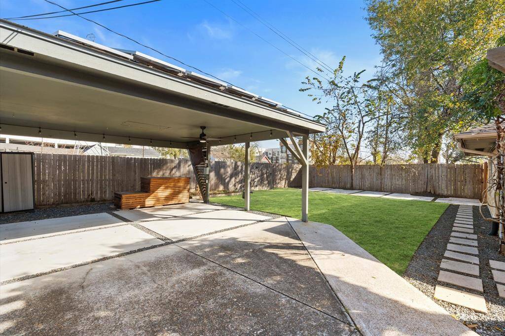 A large carport provides ample space for two cars, secured by a driveway gate. Carport also features a 220v outlet for EV charging, along with a ceiling fan and TV setup, perfect for entertaining large outdoor gatherings. Hardscaping installed in the back yard to maximize usability.