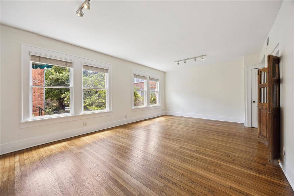 Large living with abundant natural light that has been freshly painted with newly refinished original hardwood floors overlooking a lush and serene courtyard.