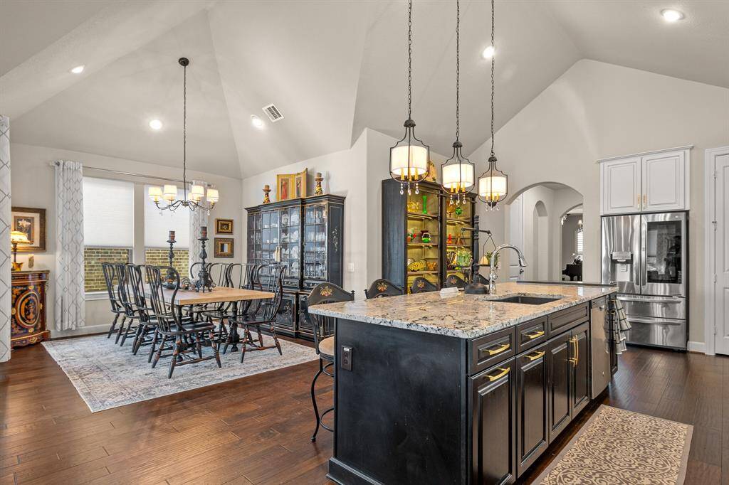 Discover this Elegant open-concept kitchen and dining area, featuring a spacious granite island, modern pendant lighting, and stainless steel appliances. The dining space boasts a large table to support multiple seating opportunities and high ceilings that enhance the airy, sophisticated ambiance.