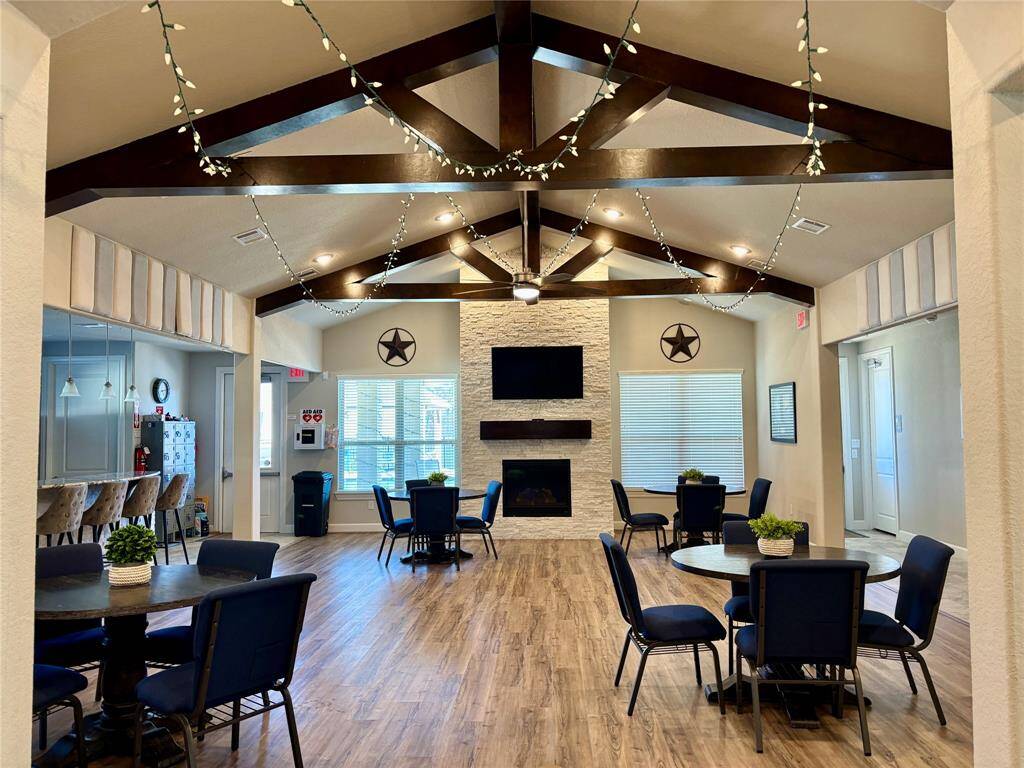 This inviting Clubhouse Community room features a fireplace, a TV, and multiple seating areas and a full Kitchen with tables for your entertainment.