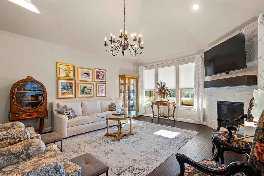 Your Living room features high ceilings and relaxed atmosphere with a gas fireplace. Large windows provide abundant natural light, and a view of the Community Lake, while a chandelier adds a touch of sophistication.