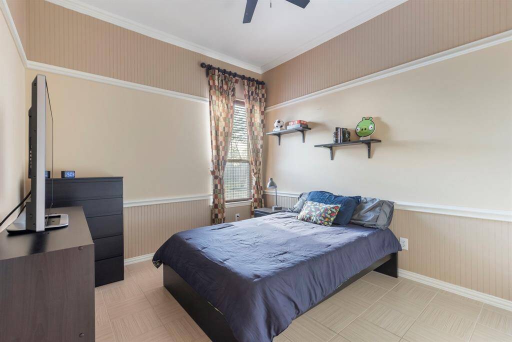 This cozy bedroom features a neutral color palette with wainscoting and crown molding.