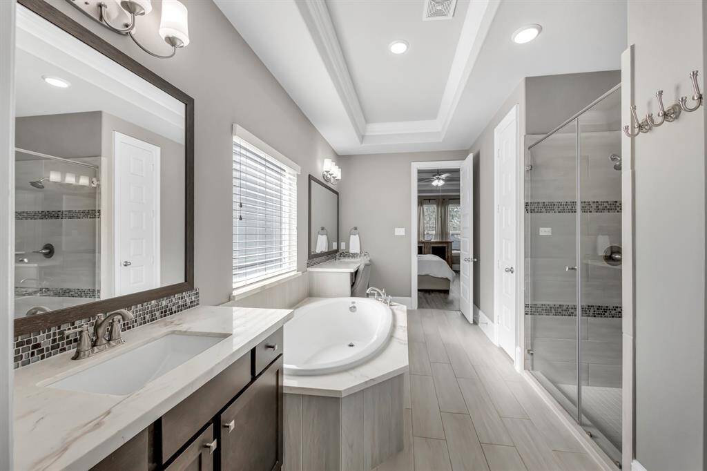 Primary Bath is equipped with garden tub, glass tile accents, spacious walk-in shower with seating and dual sinks with separate vanities for convenience.  This bath is gorgeous.