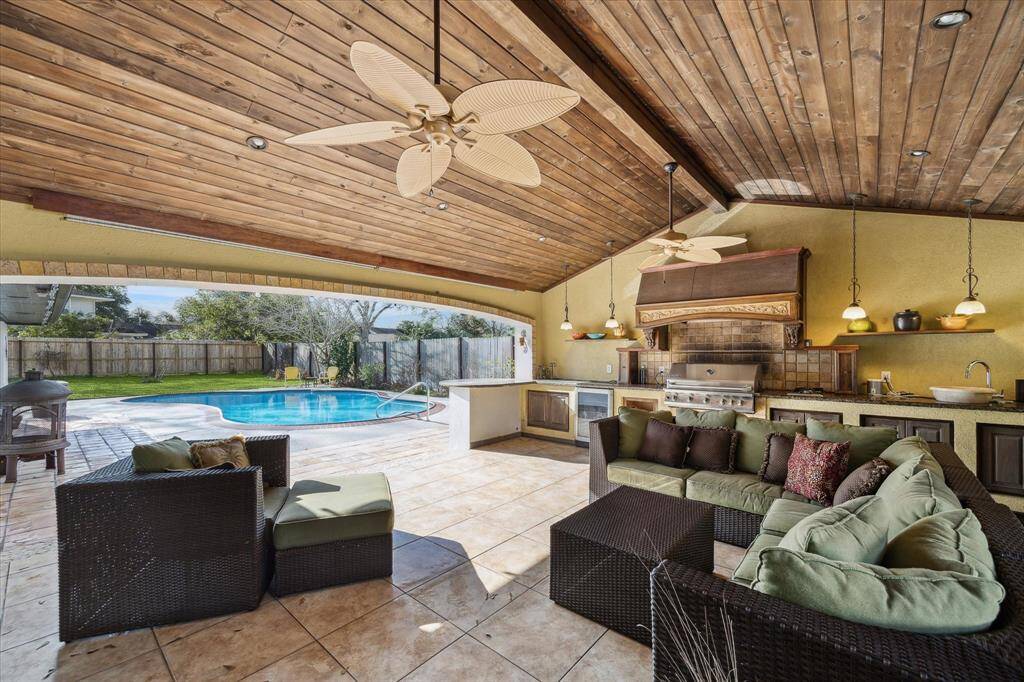 Experience vacation-style living every day!! This massive covered back patio has it all. Full kitchen, wood beam ceiling with recessed lighting and double ceiling fans, and access to the atrium with the 3-tiered fountain creates the perfect ambiance.