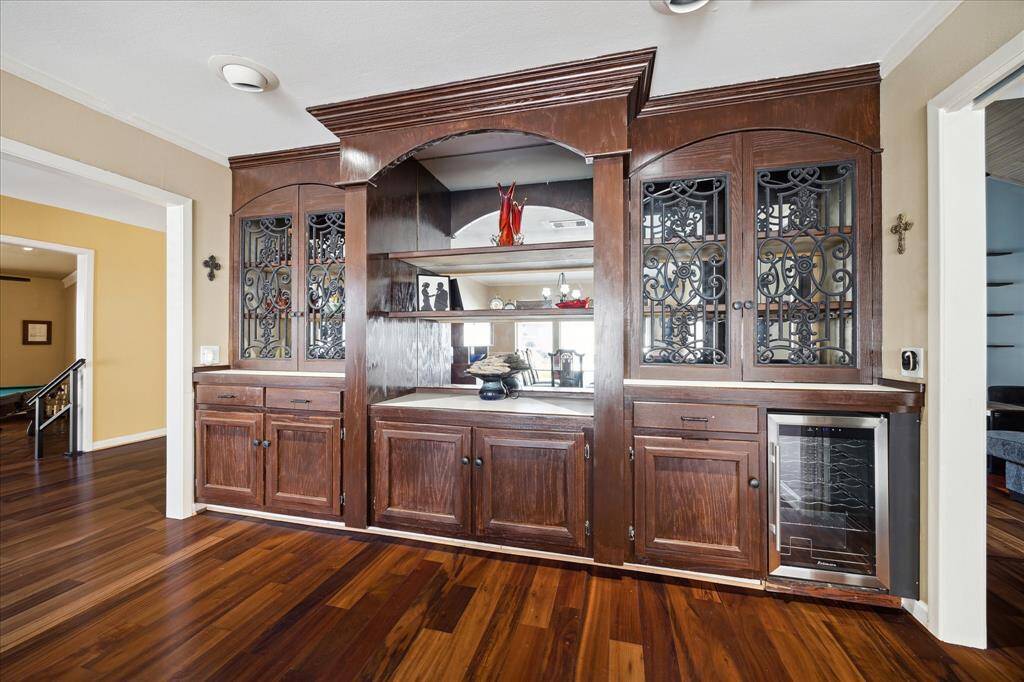 This inviting breakfast/living area features high ceilings, plantation shutters, wood flooring, and ample natural light from large windows.