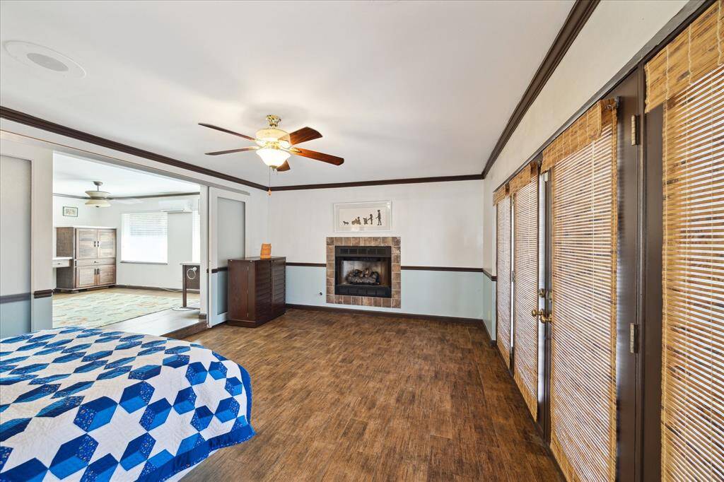 This spacious primary suite features porcelain tile floors, a cozy gas fireplace, and ample natural light from large windows with bamboo blinds. Double sliding glass doors separate from HUGE primary ensuite.