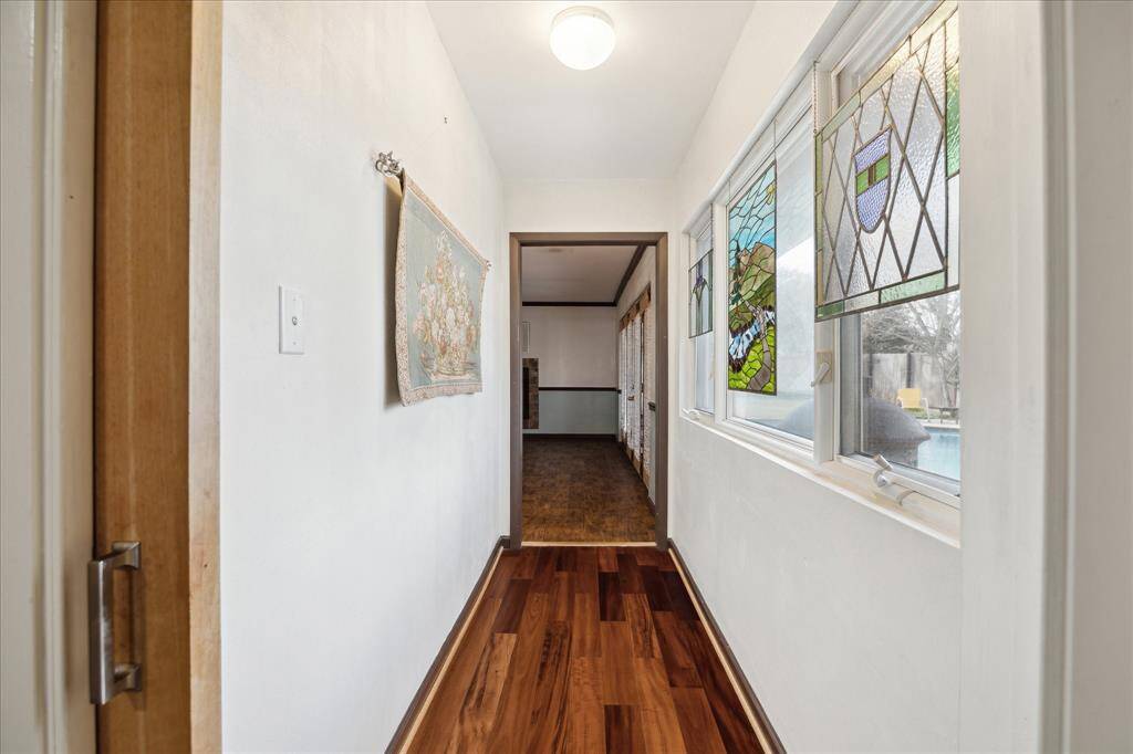 This cozy bedroom features rich wood flooring, a ceiling fan, and shares jack-and-jill ensuite with other secondary bedroom
