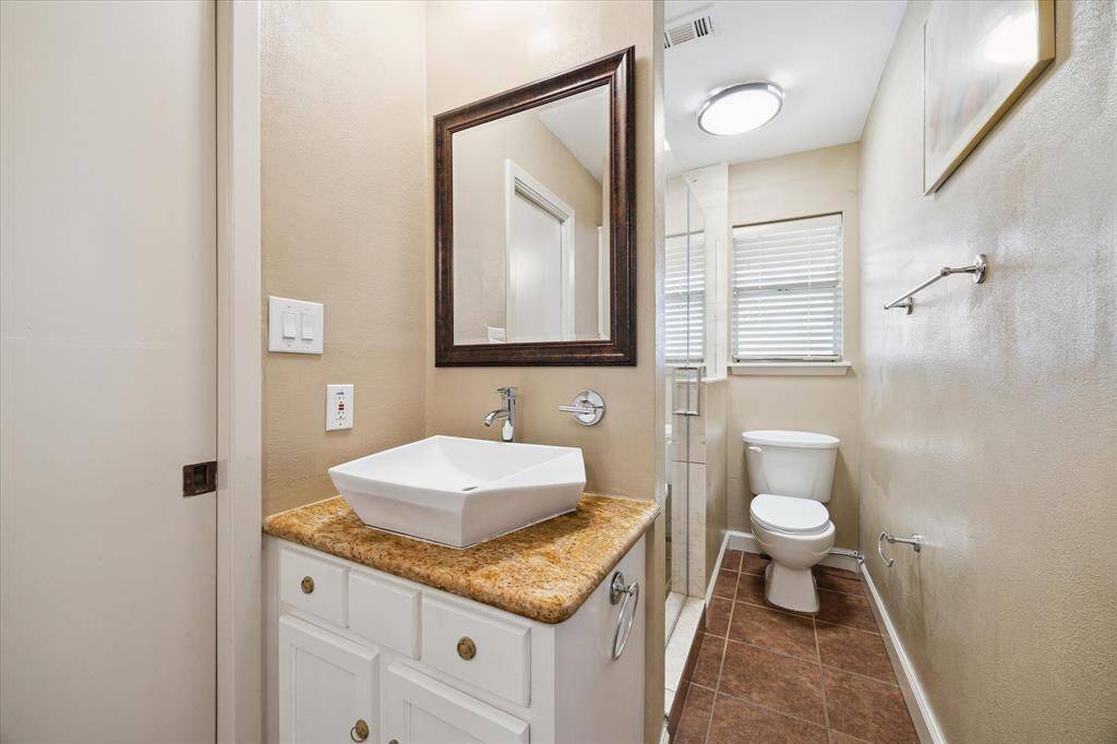 This is a compact, modern bathroom featuring a walk-in shower with glass doors. Look closely!  The faucet to the right of the sink faucet is an extra control for the shower as well so you can get that warmed up while brushing your teeth :)