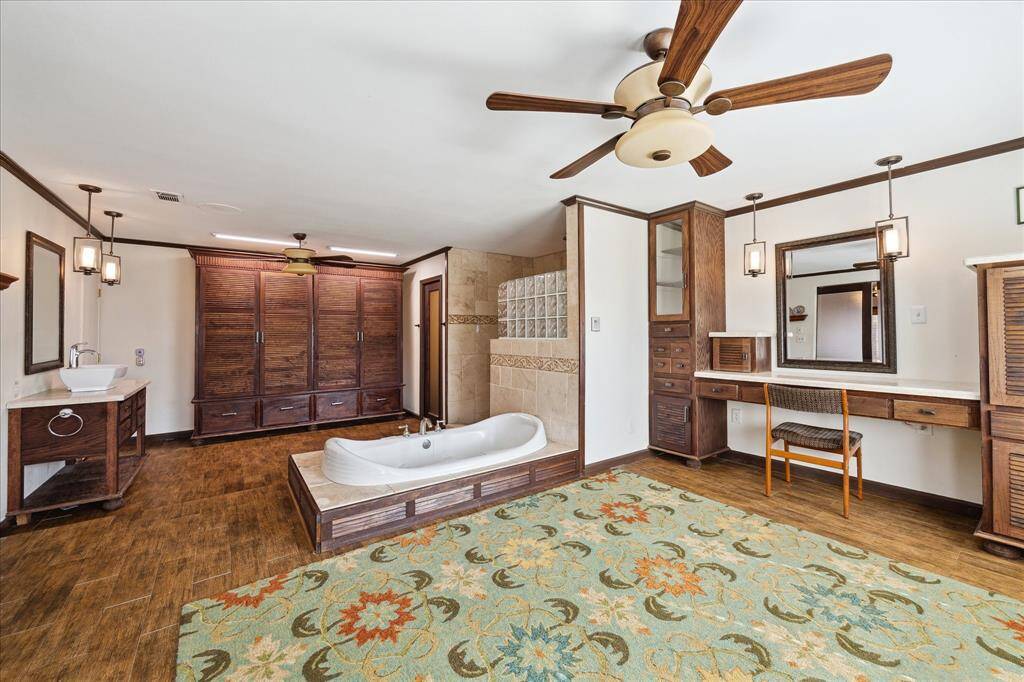 This secondary bedroom features wood flooring, a ceiling fan, and a glass door to the backyard.  Natural light filters in through sliding glass doors, creating a bright and inviting space.