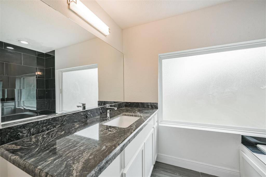Wide dual vanities w/ privacy window allows diffused light to flow in.