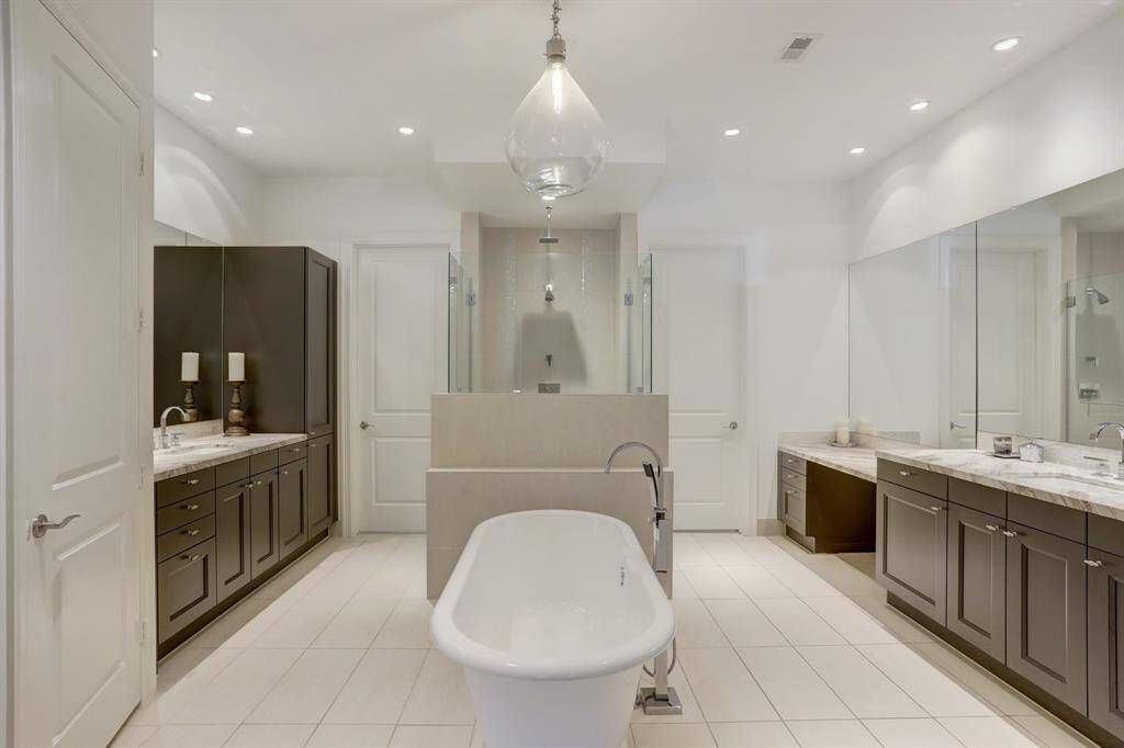 Large primary bathroom features separate vanities, soaking tub, and large walk-in shower. There is also 1 large walk-in closet with plenty of cabinet storage.